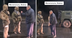 Older man speaking with Russian soldiers holding large guns