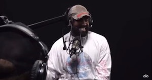 Kanye West smiling in front of a microphone for a podcast recording