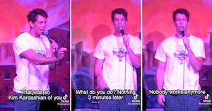 Stand-up comedian in a white t-shirt on stage roasting an audience member