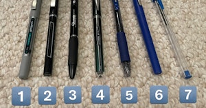 Seven different brands of pen laid out in a row on carpet labeled with numbers 1 - 7